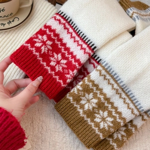 Close-up of knit leg warmers featuring festive snowflake patterns and ribbed cuffs