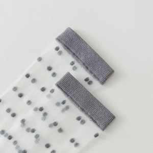 Detailed view of sheer mesh socks with gray polka dots and elastic ribbed cuffs