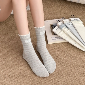 Detail of grey striped crew socks with wavy cuffs and Fashion label in a cozy home setting