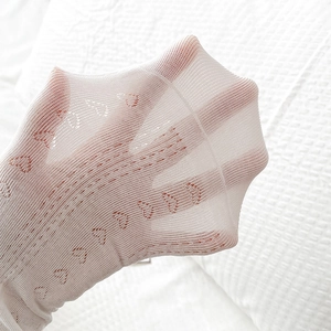 Detail showing the sheer mesh texture and hollow heart pattern of the white cotton sock