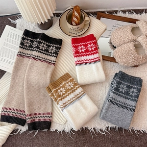 Close-up of snowflake pattern knit leg warmers in various colors with a Nordic winter style