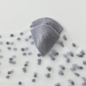 Detail of white mesh socks with black polka dots featuring a reinforced grey ribbed heel