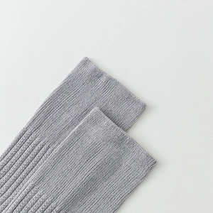 Detail of light grey knit over-knee socks featuring ribbed cuffs and fine cotton texture