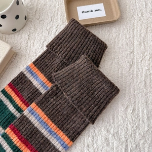 Detail of rib-knit leg warmers with colorful stripes on a soft plush background