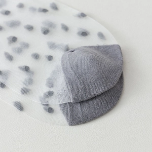 Close-up of sheer mesh polka dot socks featuring grey reinforced toes and delicate fabric