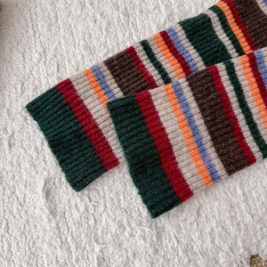 Detailed view of colorful vintage striped rib knit leg warmers on white fleece background