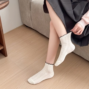 Detail of heart hollow mesh pattern and black ruffled cuffs on cream cotton socks