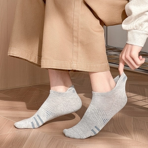 Detail of light gray mesh socks with blue stripes and heel tab on wooden floor