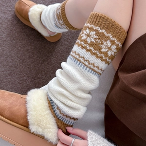 Detail of knitted leg warmers with snowflake pattern and ribbed texture in beige and brown