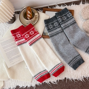 Detailed close-up of thick winter leg warmers featuring retro snowflake jacquard patterns