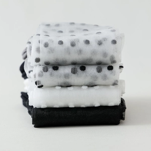 Detail of stacked breathable mesh socks with polka dot patterns and solid colors