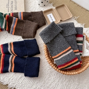 Detail of vintage striped chunky knit leg warmers in brown, blue, and grey wool textures