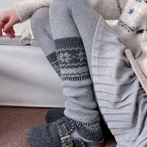 Detail of grey knitted leg warmers with snowflake jacquard pattern and ribbed cuffs