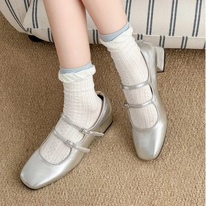 Silver Mary Jane shoes with double straps and square toe on light brown carpet