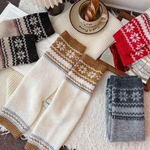 Close-up of Nordic knit leg warmers with snowflake patterns on a cozy winter carpet
