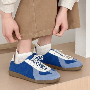 Close-up of men's blue suede German army trainers with gum soles on wooden floor