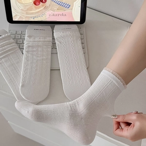 Detailed knit patterns of white crew socks showing cable knit and lettuce edge textures