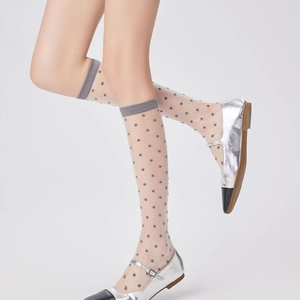Detailed view of sheer polka dot knee-high socks paired with silver Mary Jane shoes