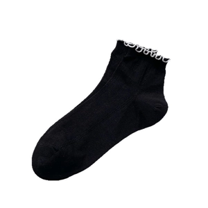 Black cotton socks with white ruffle trim and ribbed texture shown at a 45-degree angle