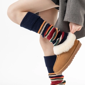 Detail of striped knitted leg warmers with fleece-lined brown suede boots in winter style
