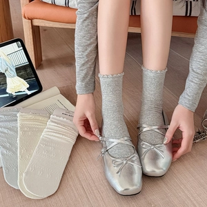 Silver Mary Jane shoes paired with ruffled knit socks in a bright home setting