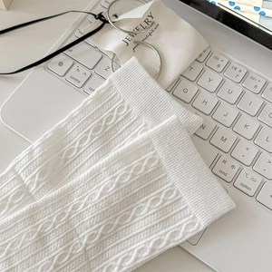 Detail of white cable knit texture on minimalist Japanese style socks over a laptop