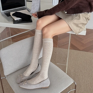 Detail of beige knee-high socks featuring diamond knit texture and scalloped edges
