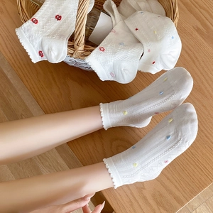 Detail of white mesh socks with floral embroidery and wavy ruffled cuffs in a basket