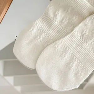 Macro shot of white knitted socks featuring intricate 3D diamond texture and jacquard knit