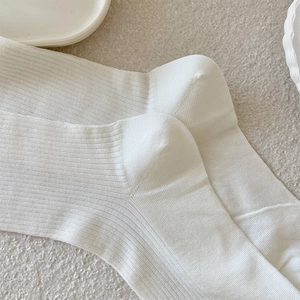 Detailed macro view of white ribbed texture and reinforced heel seam on long cotton socks