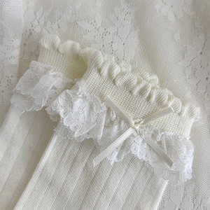 Détail de chaussettes blanches Lolita avec bordure en dentelle et un petit nœud fin