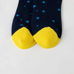 Macro shot of knitted cotton crew sock featuring blue stars and vibrant yellow toe detail