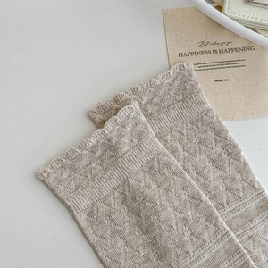 Detail of light beige knit high socks featuring classic diamond lattice jacquard texture