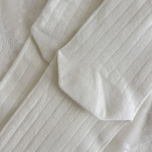 Gros plan de chaussettes en coton côtelé blanc montrant la texture de tissage verticale