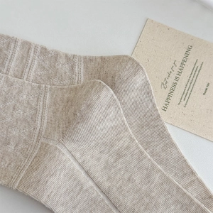 Close-up of oatmeal knit high socks featuring delicate textured diamond patterns