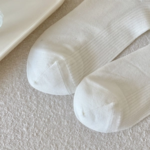 Close-up of white vertical ribbed knit cotton socks showing detailed toe seam and texture