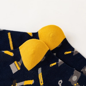 Detailed macro view of navy blue cotton sock featuring yellow tool patterns and reinforced heel