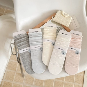 Close-up of five pairs of pastel knit socks with floral lace texture and wavy ruffled edges