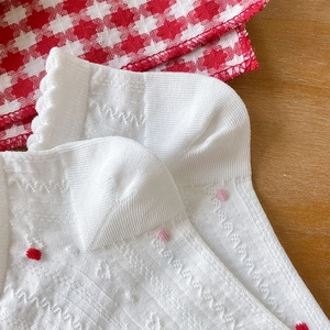 Detail of white lace knit socks with red heart embroidery and breathable mesh texture