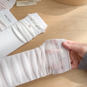 Close-up of white lace crew socks featuring floral mesh texture and brand label detail