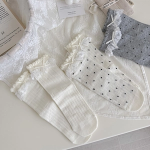 Détail de trois paires de chaussettes en dentelle Lolita avec nœuds en blanc et gris
