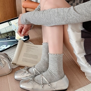Silver Mary Jane shoes paired with grey ruffle knit socks on wooden floor background