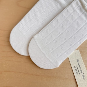 Dettaglio di calze in pizzo bianco con punta rinforzata e motivi a maglia intrecciata