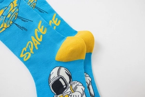 Detail of bright blue cotton crew socks featuring astronaut motifs and yellow SPACE text