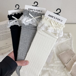 Détail de chaussettes en tricot avec dentelle délicate et nœuds en noir, gris et blanc