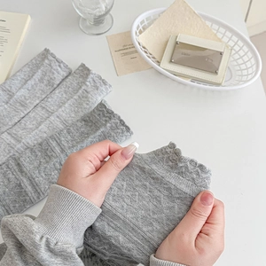 Detail showing the elastic texture and ruffled lettuce edge of gray knitted leg warmers