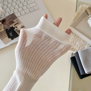 Detailed view of white knitted leg warmers with delicate vertical ribbed texture