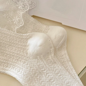 Detail weißer Spitzenstrümpfe mit Blumenmustern und bestickten Wellenkanten für Damen