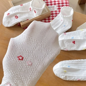 Close-up of white mesh socks with delicate embroidery and elegant wavy cuff details