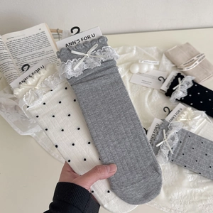 Détail des revers en dentelle avec petits nœuds sur des chaussettes Lolita à pois